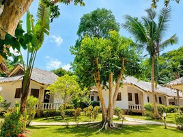 Un resort tropical con cabañas de techo de paja, exuberante follaje y cielo despejado.