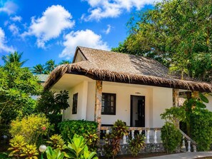 A house with a thatched roof, surrounded by lush greenery and palm trees. - Phuwadee Resort & Spa (Ko Pha-ngan)