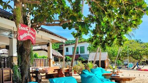 Outdoor seating with turquoise cushions, a wooden table, and a sign for 'Beach Love Restaurant'. - Phuwadee Resort & Spa (Ko Pha-ngan)