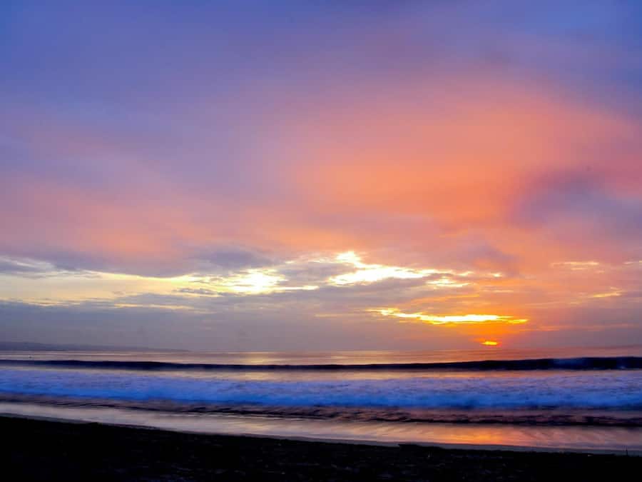 Um pôr do sol sobre o oceano com ondas.