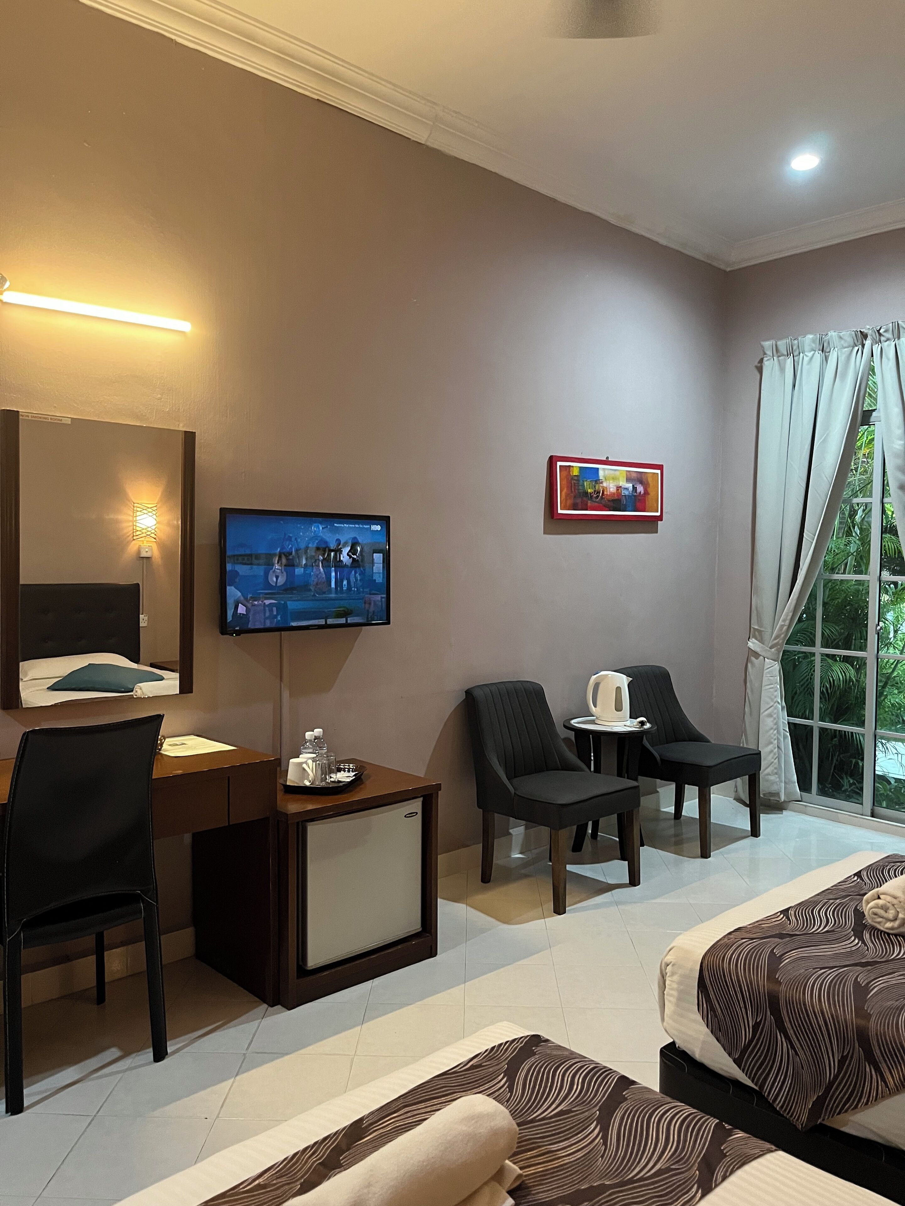 Une chambre d’hôtel équipée d’un lit, d’un bureau, d’une chaise, d’une télévision et d’une fenêtre avec des rideaux.