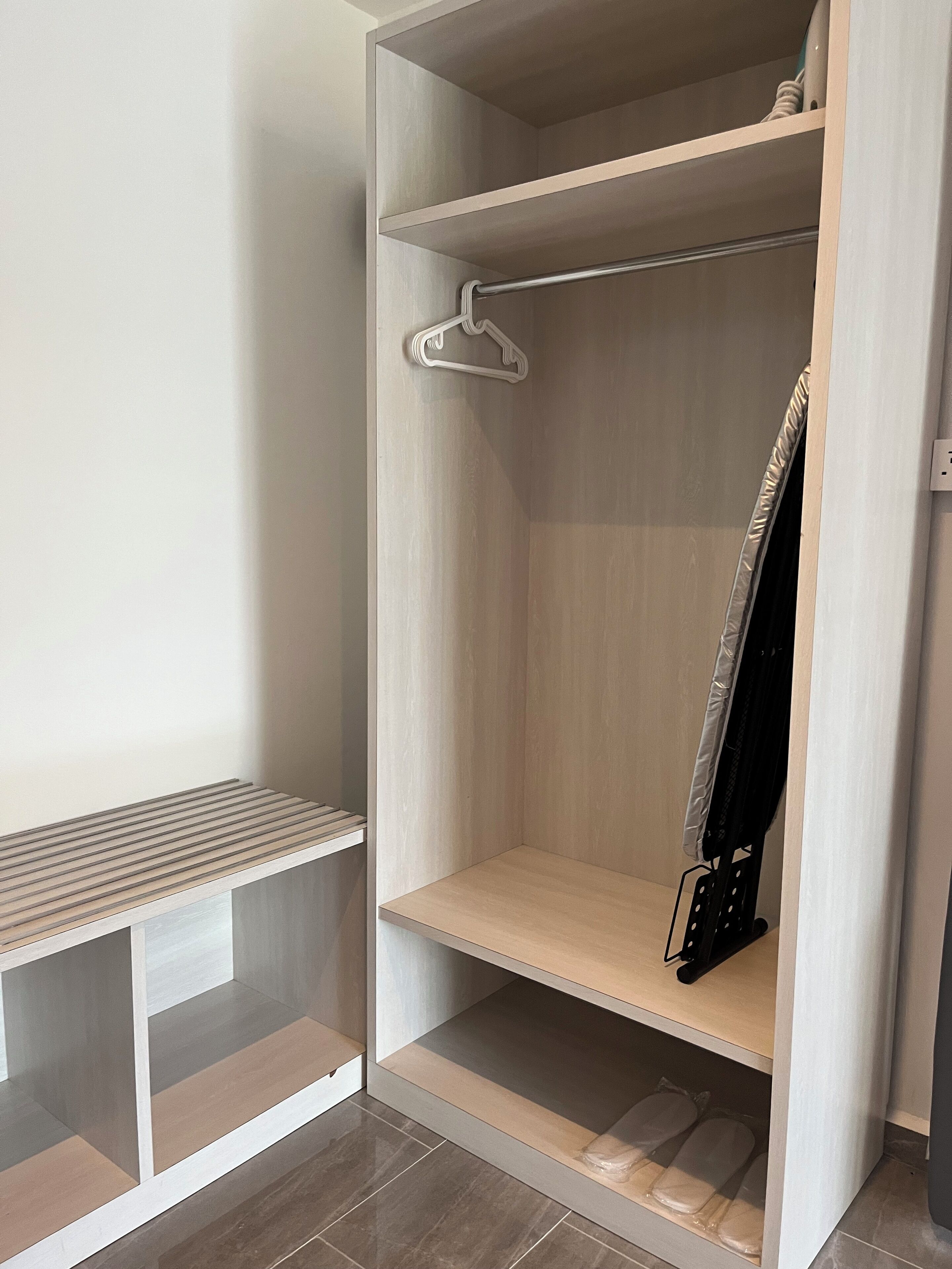 Un dressing accessible sans porte, doté d’étagères ouvertes, d’une tringle et d’un banc.