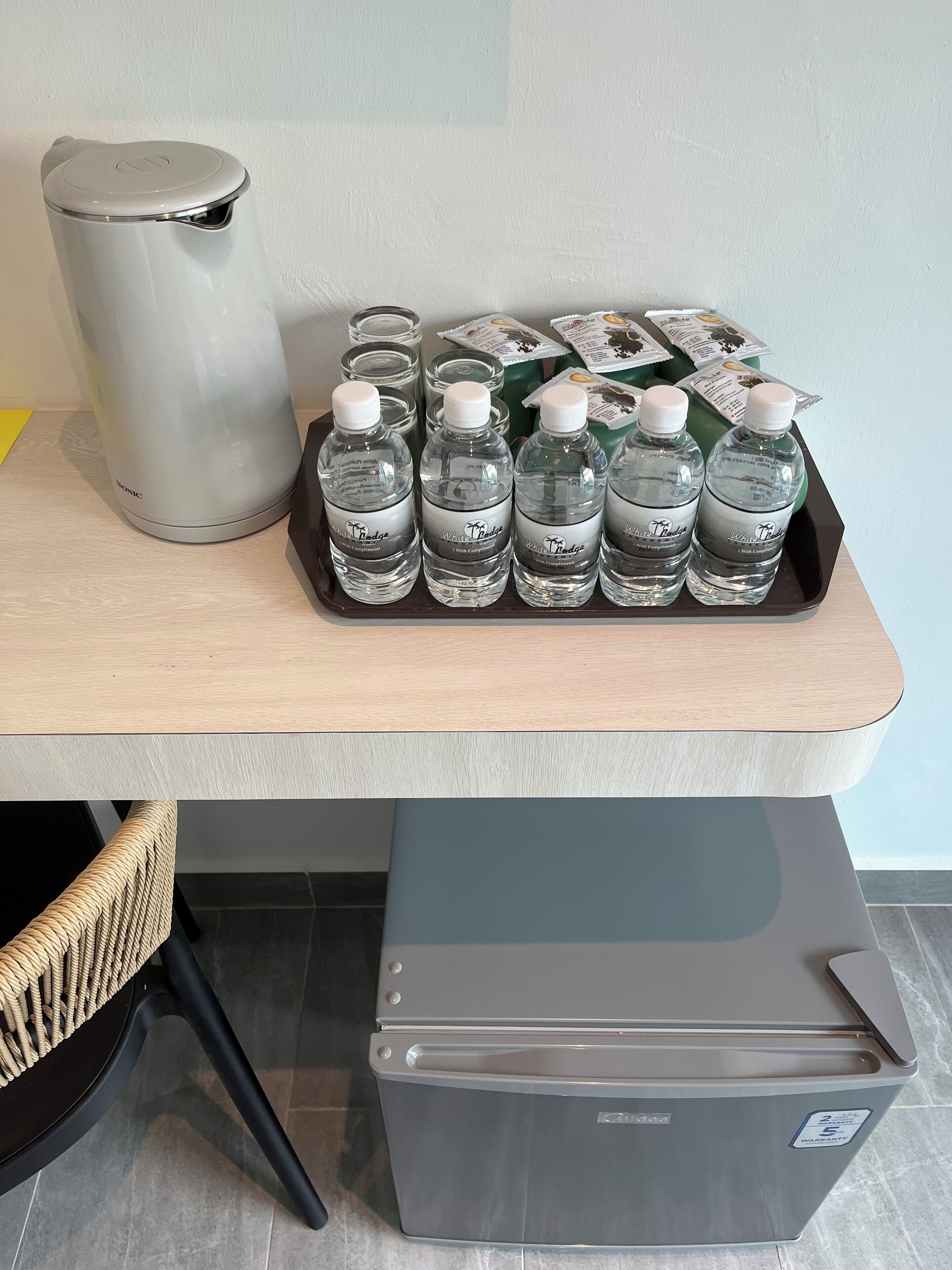 A table with a trash can, a tray of water bottles, and a box.