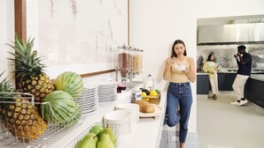 A modern kitchen with a breakfast bar, fruit bowls, and a coffee station.
