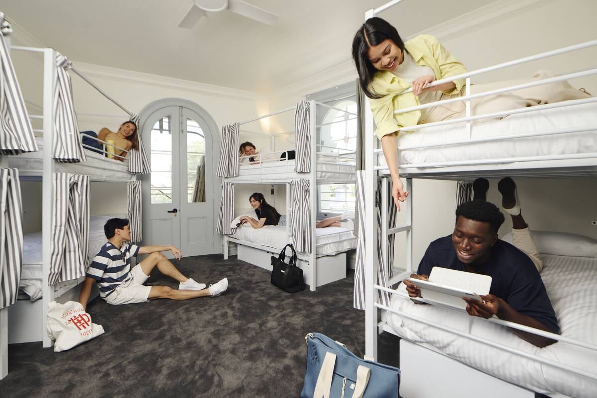 A dormitory-style room with bunk beds, a door, and a window.