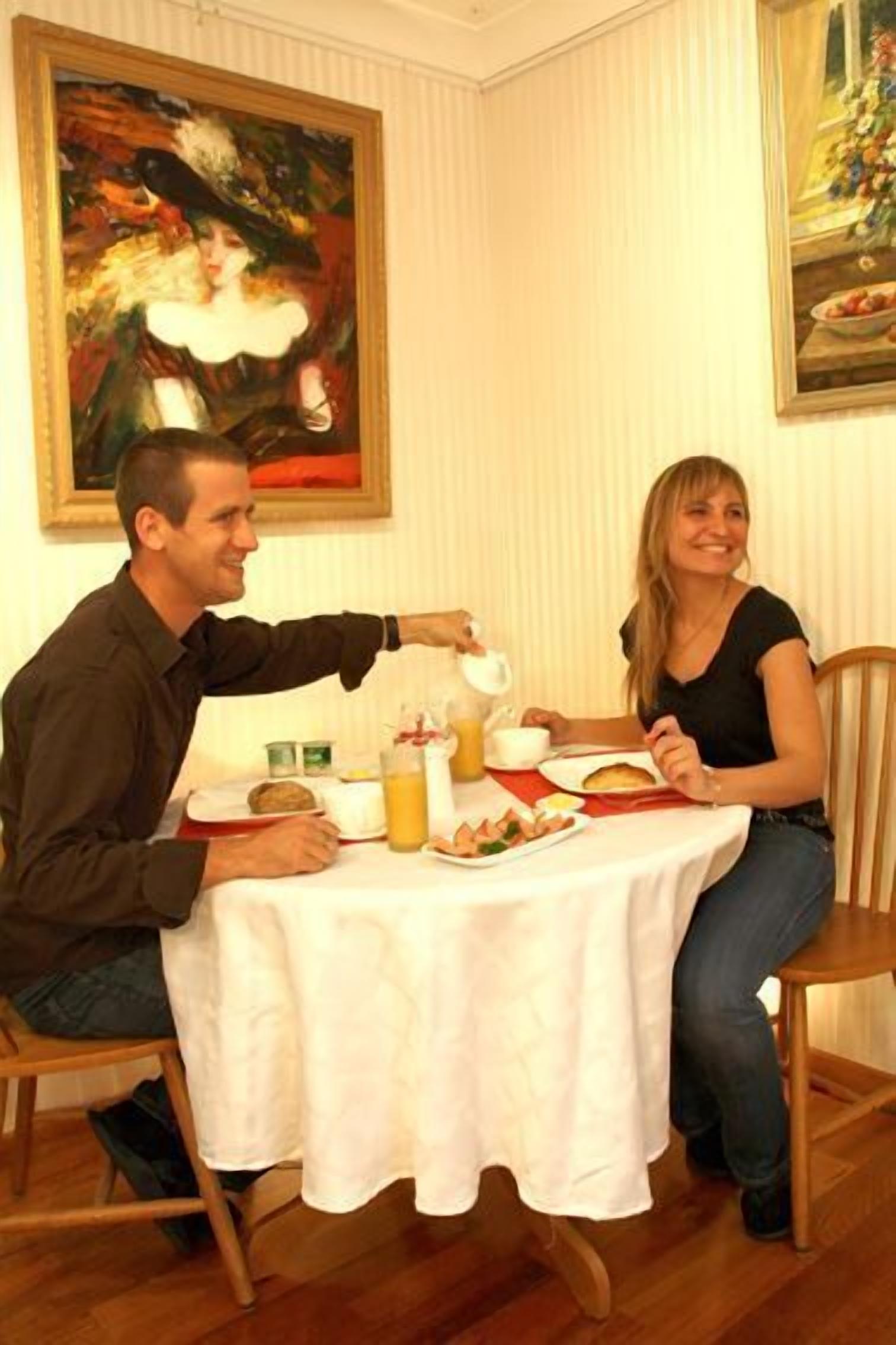 Una mesa de comedor con mantel blanco, platos de comida y una jarra de jugo.