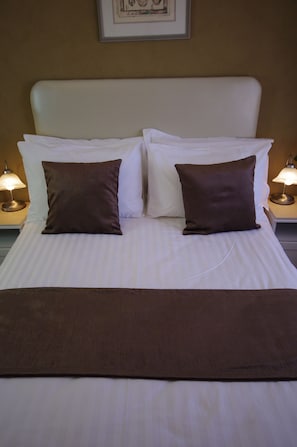 A neatly made bed with white linens and two brown pillows, flanked by two bedside lamps on matching nightstands. - Astoria Retreat B&B (Alexander Heights)