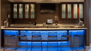 Une cuisine moderne dotée d’un coin bar, comprenant un téléviseur à écran plat, des meubles en bois et des tabourets de bar.