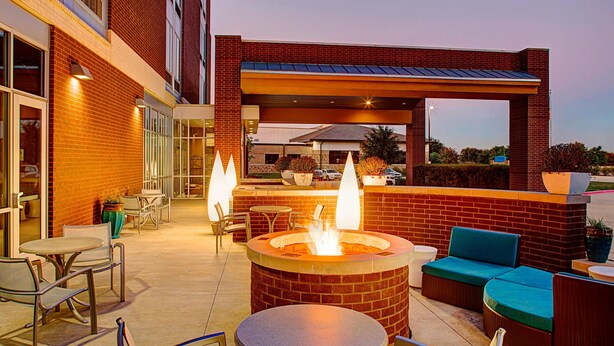 Une terrasse extérieure avec un foyer, des sièges et des tables.