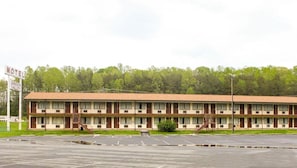 Un motel con una estructura de dos pisos, un estacionamiento y un letrero que indica el nombre y la ubicación del motel.