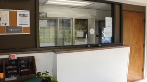 A reception desk with a bulletin board, a window with blinds, and a wooden door.