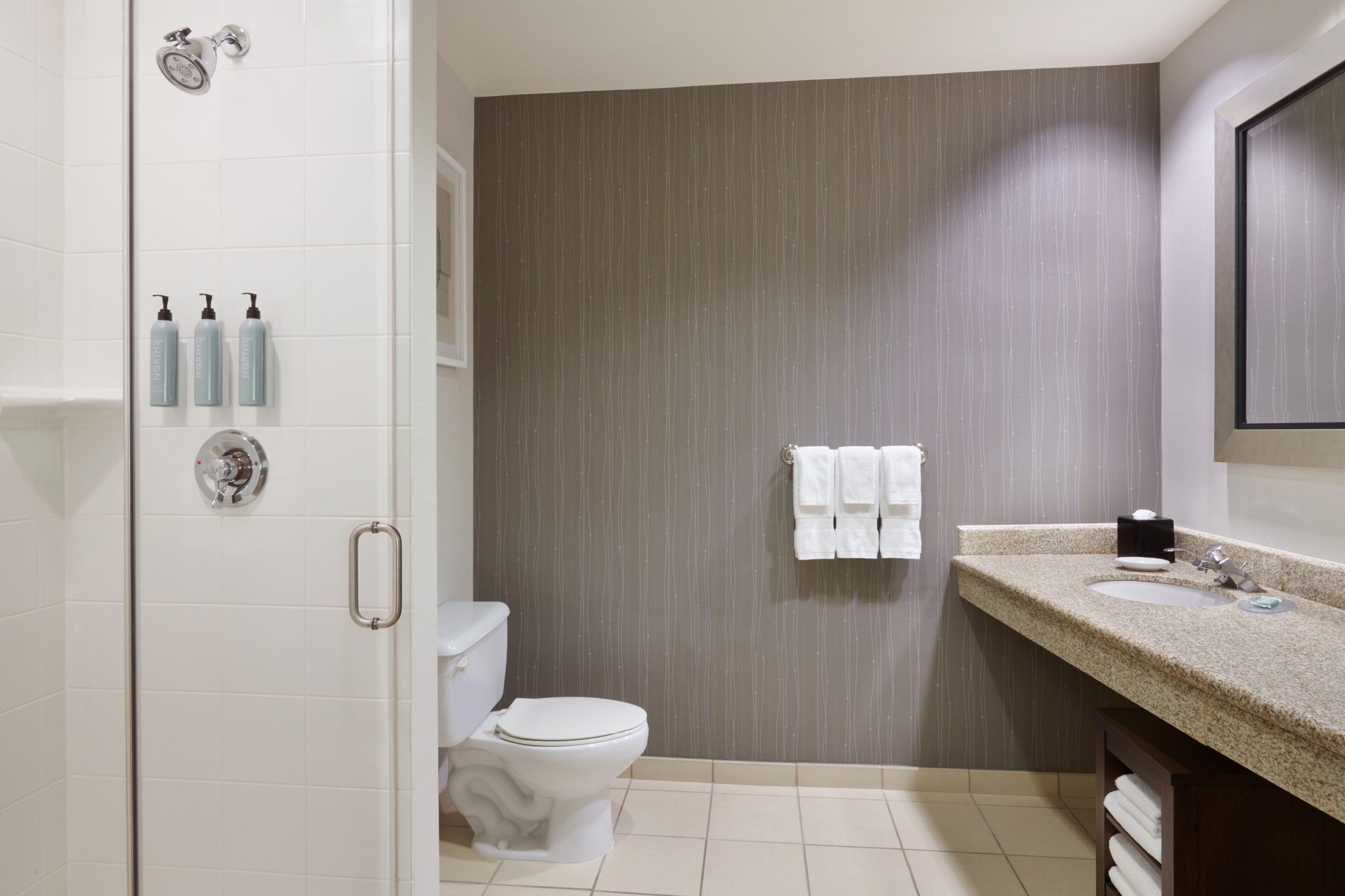 A modern bathroom with a toilet, shower, and sink.