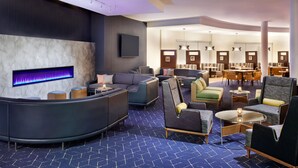 A modern lobby with a curved reception desk, multiple seating areas, and a large wall-mounted TV. - Courtyard by Marriott Ottawa East (Ottawa)