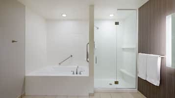 Un baño moderno con bañera, ducha con mampara de vidrio y un perchero para toallas.