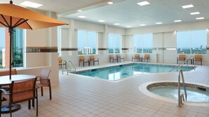 A hotel pool area with a view of the city, a table with chairs, and an umbrella. - Courtyard by Marriott Ottawa East (Ottawa)
