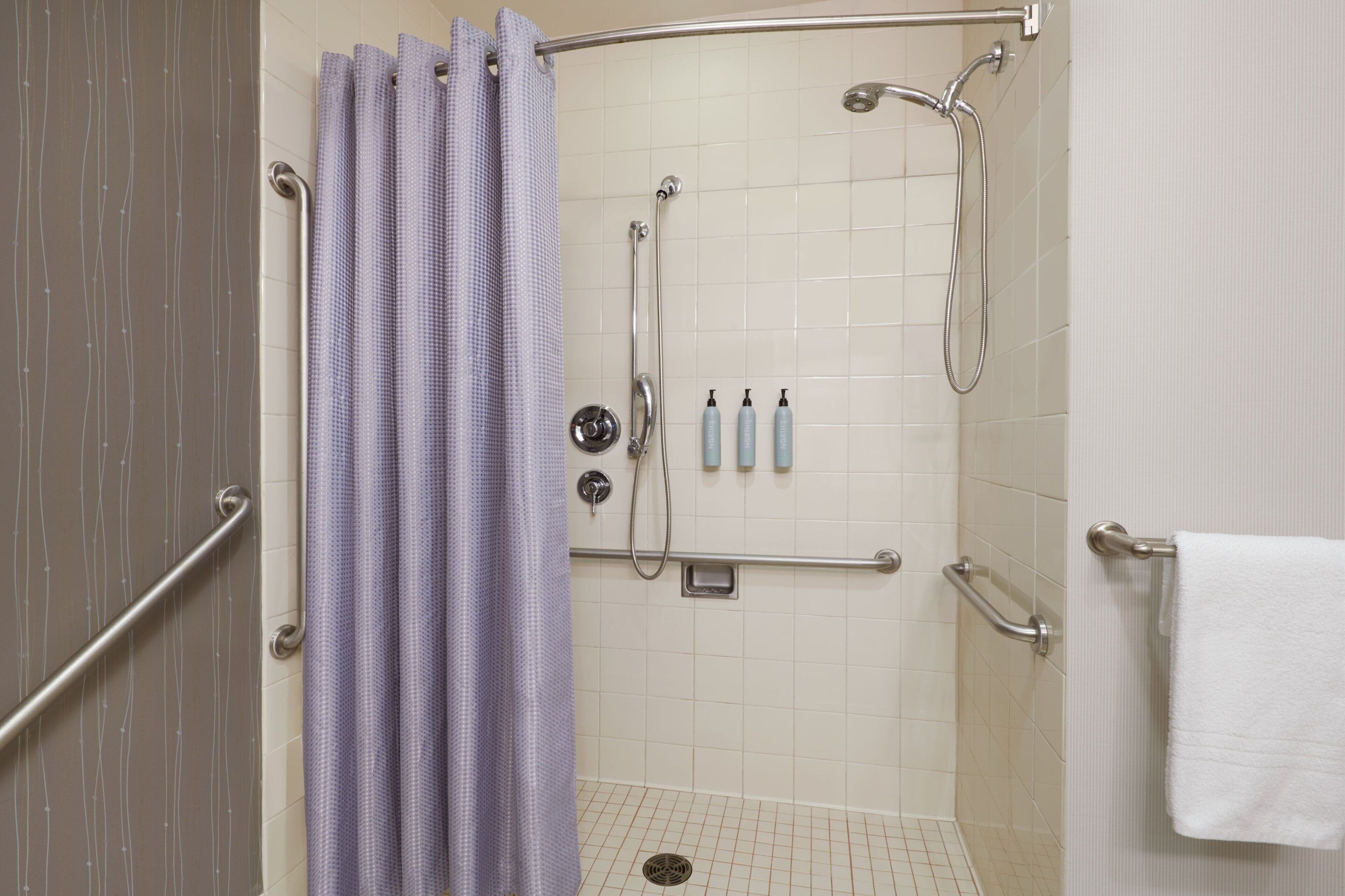 A shower area with a grab bar, a showerhead, and a towel rack.