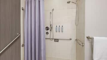 A shower area with a grab bar, a showerhead, and a towel rack.