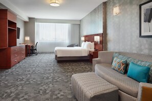 A hotel room with a bed, a sofa, a desk, and a wardrobe. - Courtyard by Marriott Ottawa East (Ottawa)