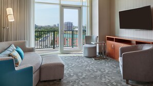A hotel room with a large window, a flat-screen TV, a sofa, a chair, and a small table. - Courtyard by Marriott Ottawa East (Ottawa)