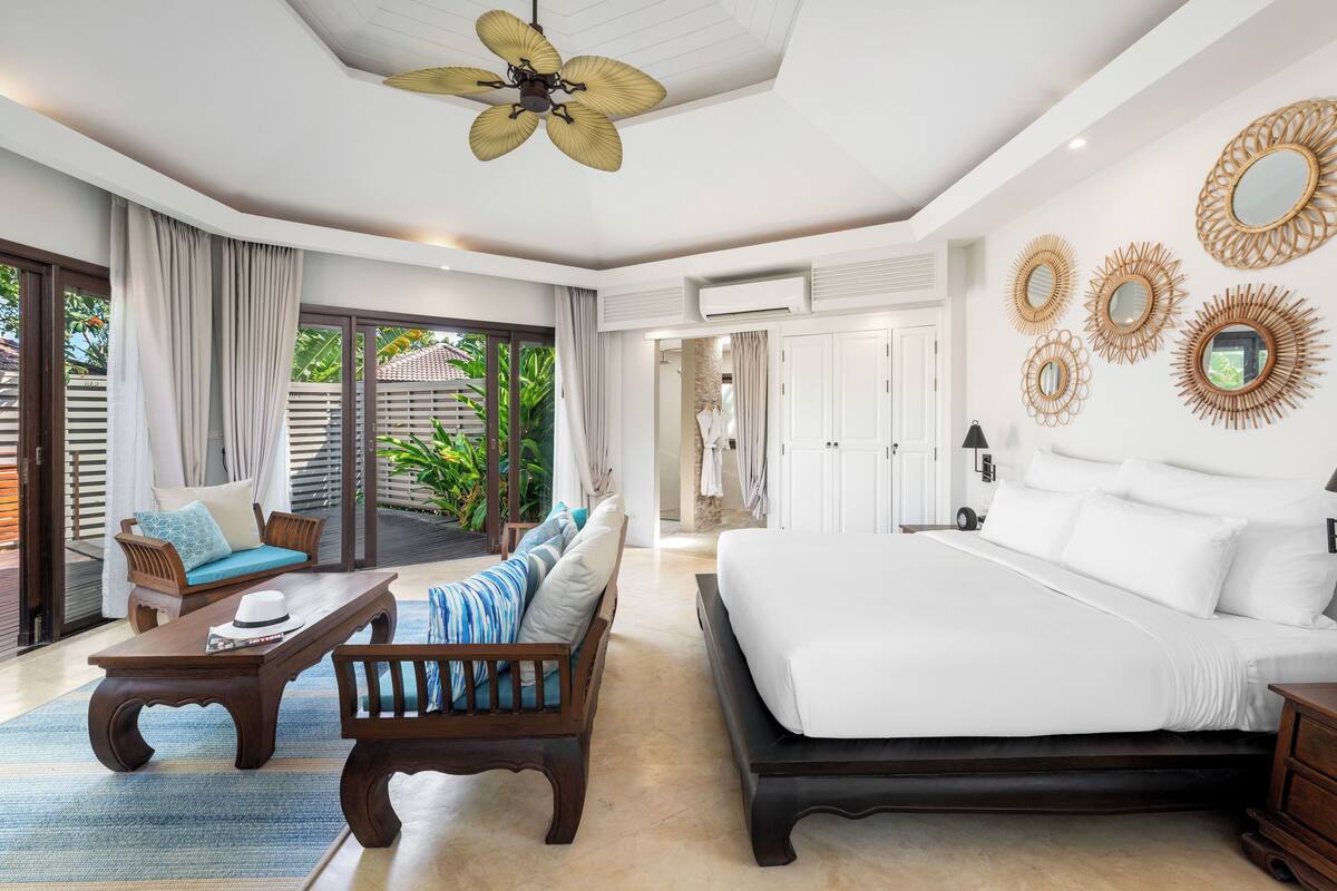A spacious bedroom with a large bed, a ceiling fan, and a view of the outdoors.
