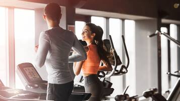 A gym with exercise equipment and large windows.