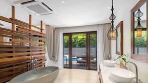 A modern bathroom with a large bathtub, two sinks, and a view of an outdoor pool area. - SAii Koh Samui Villas - Adults Only (Koh Samui)