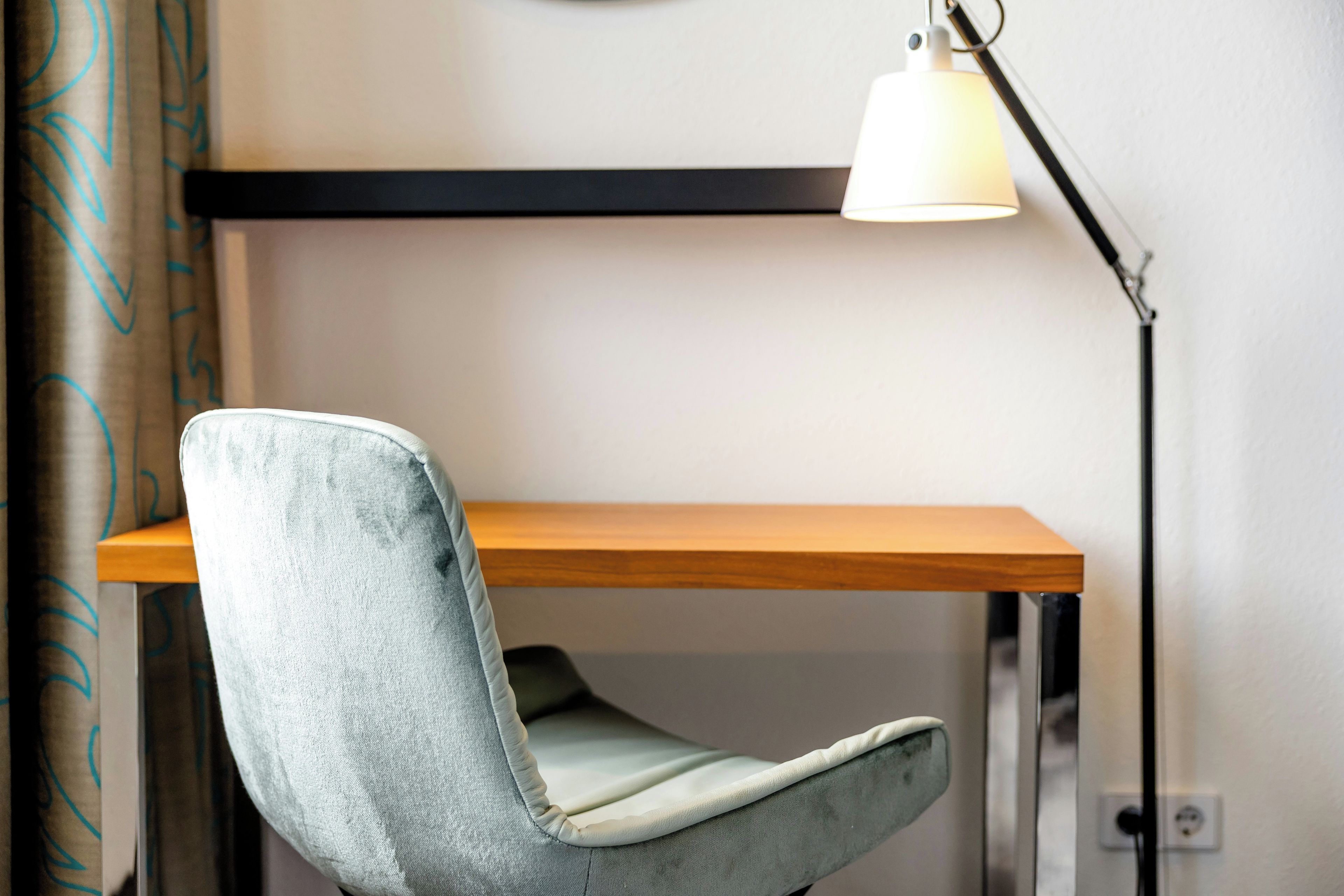 Una silla con respaldo acolchado y un escritorio de madera con estructura metálica.