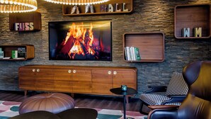 Una sala moderna con un televisor grande, estantes de madera y una chimenea.