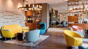 Un moderno vestíbulo de hotel con un sofá amarillo, un sillón azul y una estantería de madera.