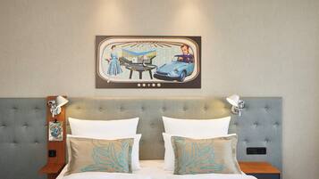 A hotel room with a tufted headboard, two bedside tables with lamps, a bed with white linens, and a wall-mounted picture of a vintage car scene.