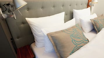 A hotel room with a tufted headboard, white bedding, and decorative pillows.