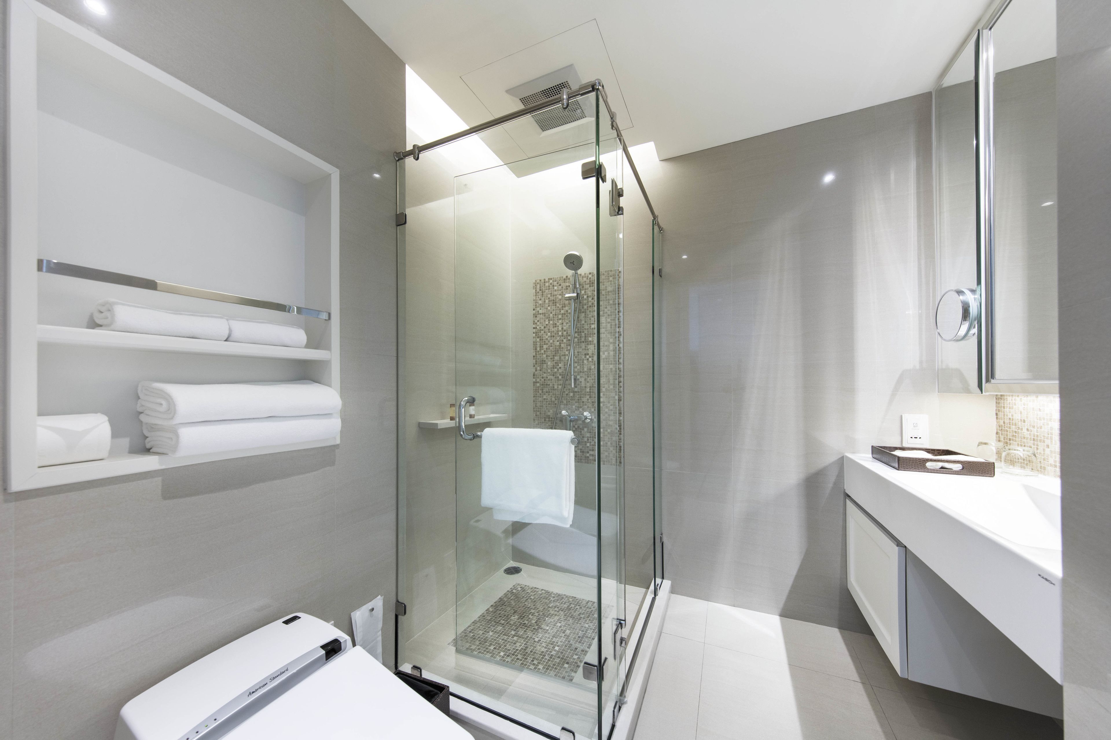 A modern bathroom with a glass-enclosed shower, a white sink, and a towel rack.