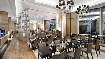 A modern restaurant with a long counter, multiple tables, and a central bar area.
