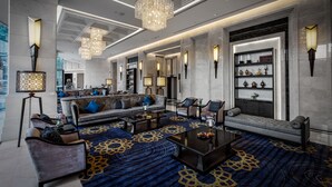 A spacious lobby with a grand chandelier, seating areas, and a decorative wall with shelves. - Grande Centre Point Hotel Terminal 21 (Bangkok)