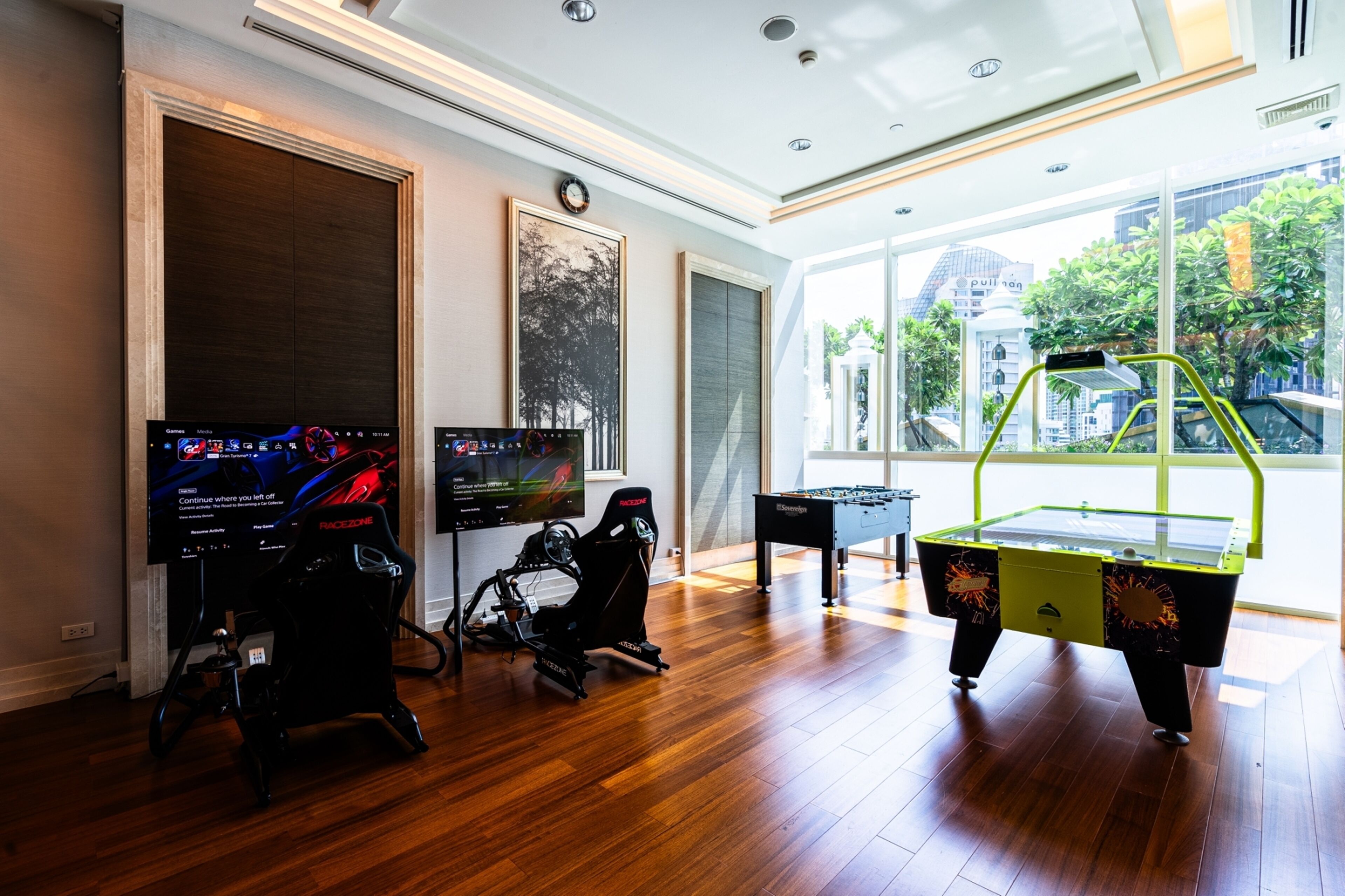 A modern room with a foosball table, two exercise bikes, and a large TV screen.