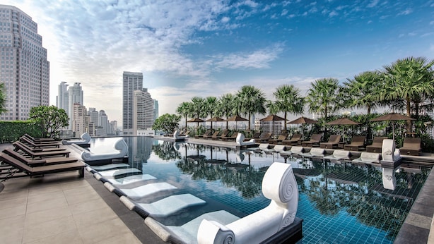 A rooftop infinity pool with lounge chairs, palm trees, and high-rise buildings in the background. - Grande Centre Point Hotel Terminal 21 (Bangkok)