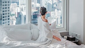 A bed with white bedding and pillows, a window with a cityscape view, and a bedside table with a lamp and a tissue box. - Grande Centre Point Hotel Terminal 21 (Bangkok)