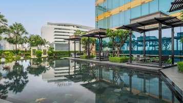 A modern hotel with a reflective pool, outdoor seating, and lush landscaping.
