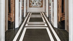 A corridor with a geometric patterned wall, chandeliers, and elevators. - Grande Centre Point Hotel Terminal 21 (Bangkok)