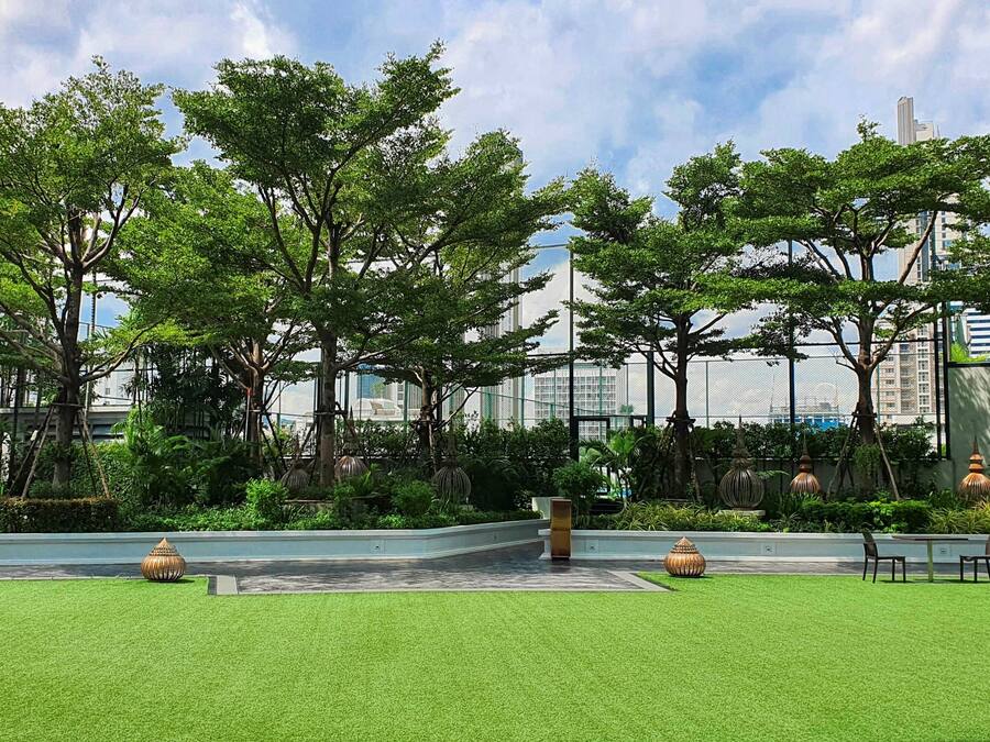 A landscaped courtyard with artificial grass, trees, and outdoor furniture.