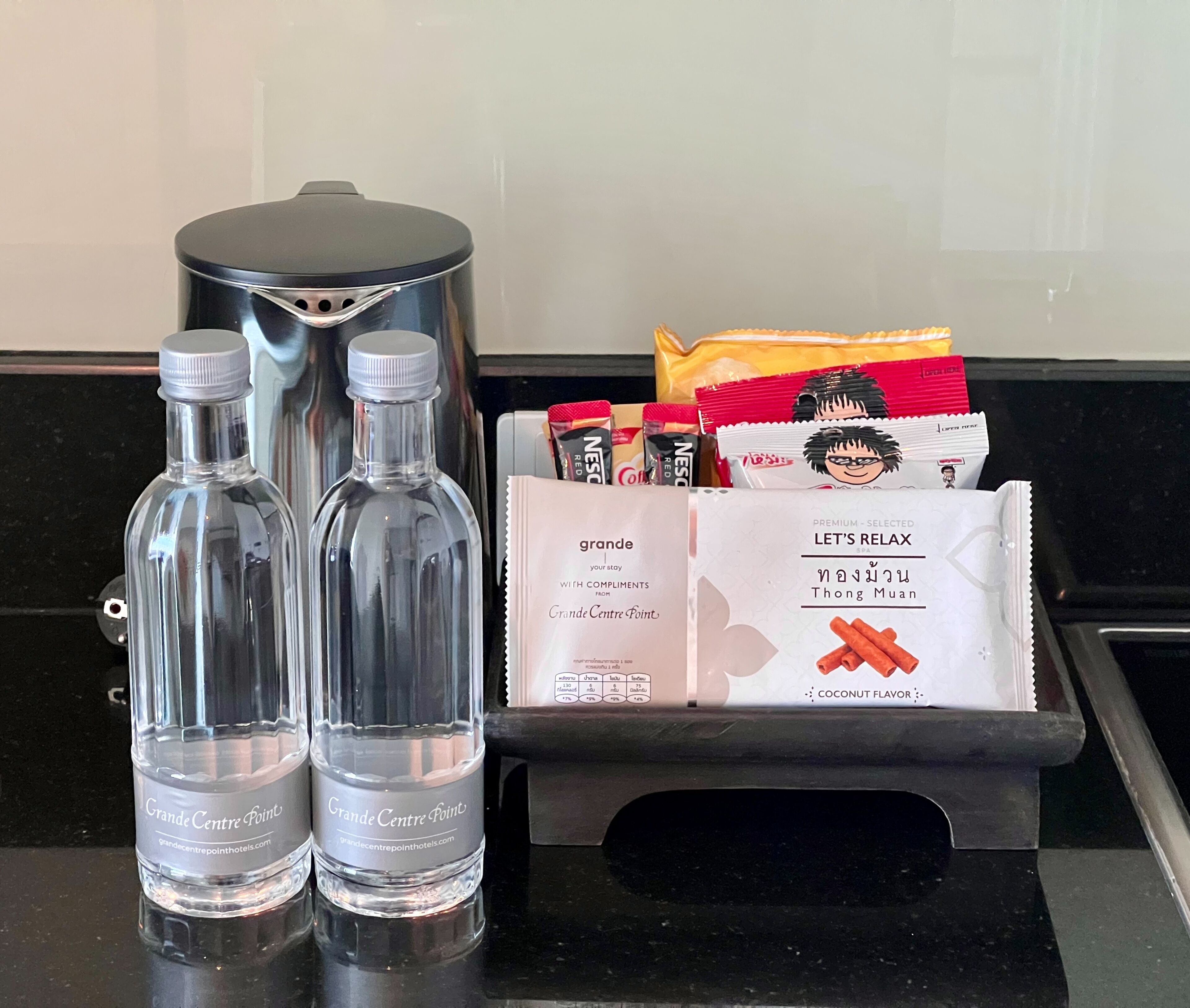Two Grande Centre Point water bottles, a coffee maker, and a selection of Nescafé coffee pods.