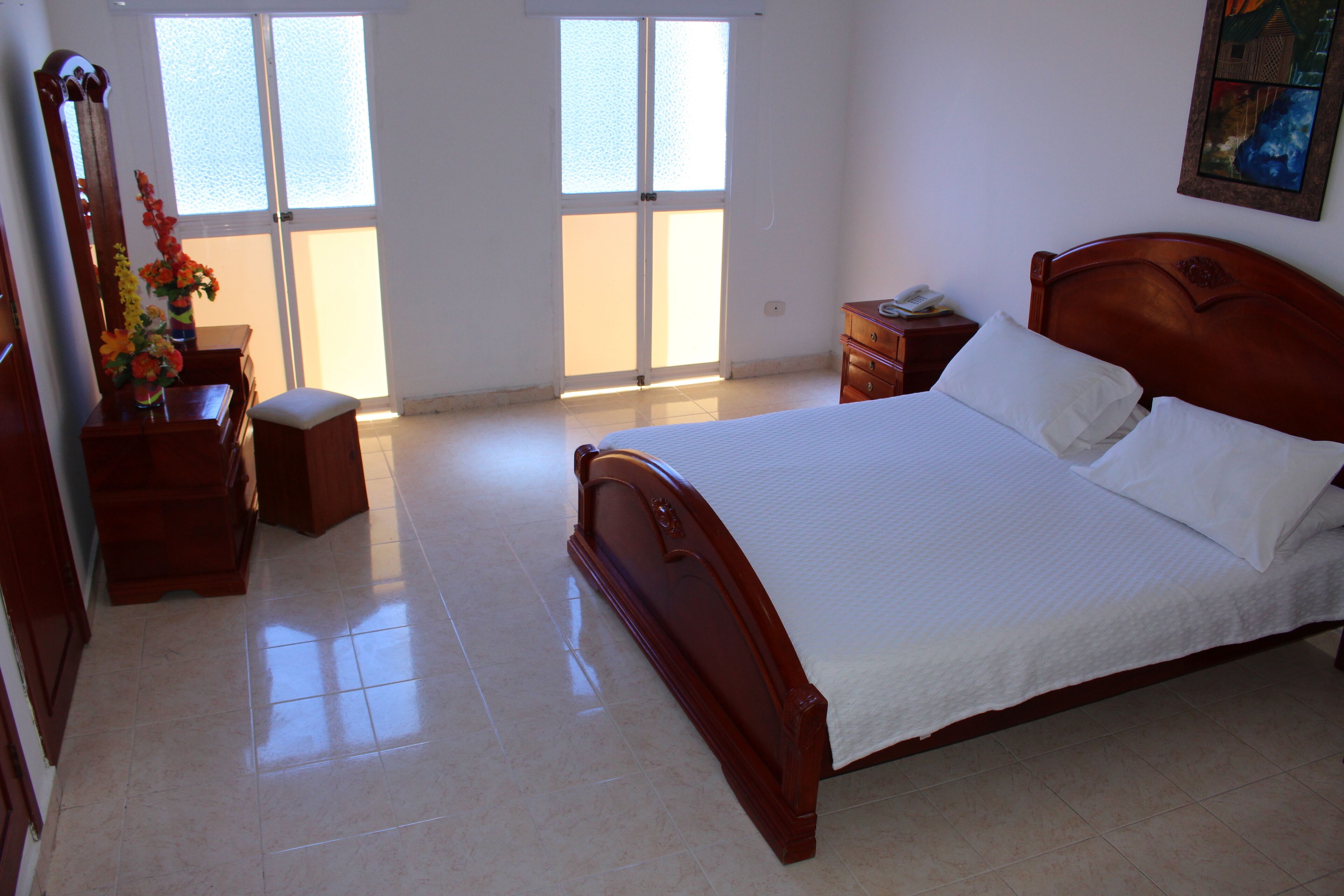 A bedroom with a wooden bed, a nightstand, a dresser, and a mirror.