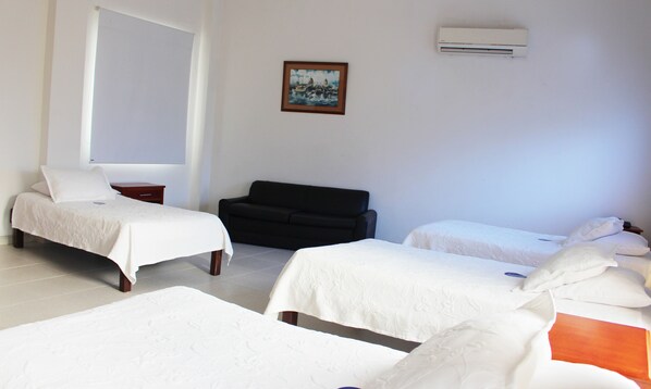 A hotel room with two single beds, a sofa, a small table, and a painting on the wall. - Hotel Dorado Plaza Centro Histórico (Cartagena)