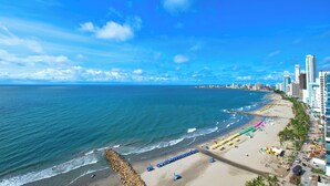 Un paisaje urbano costero con una playa, edificios altos y un cielo azul despejado.