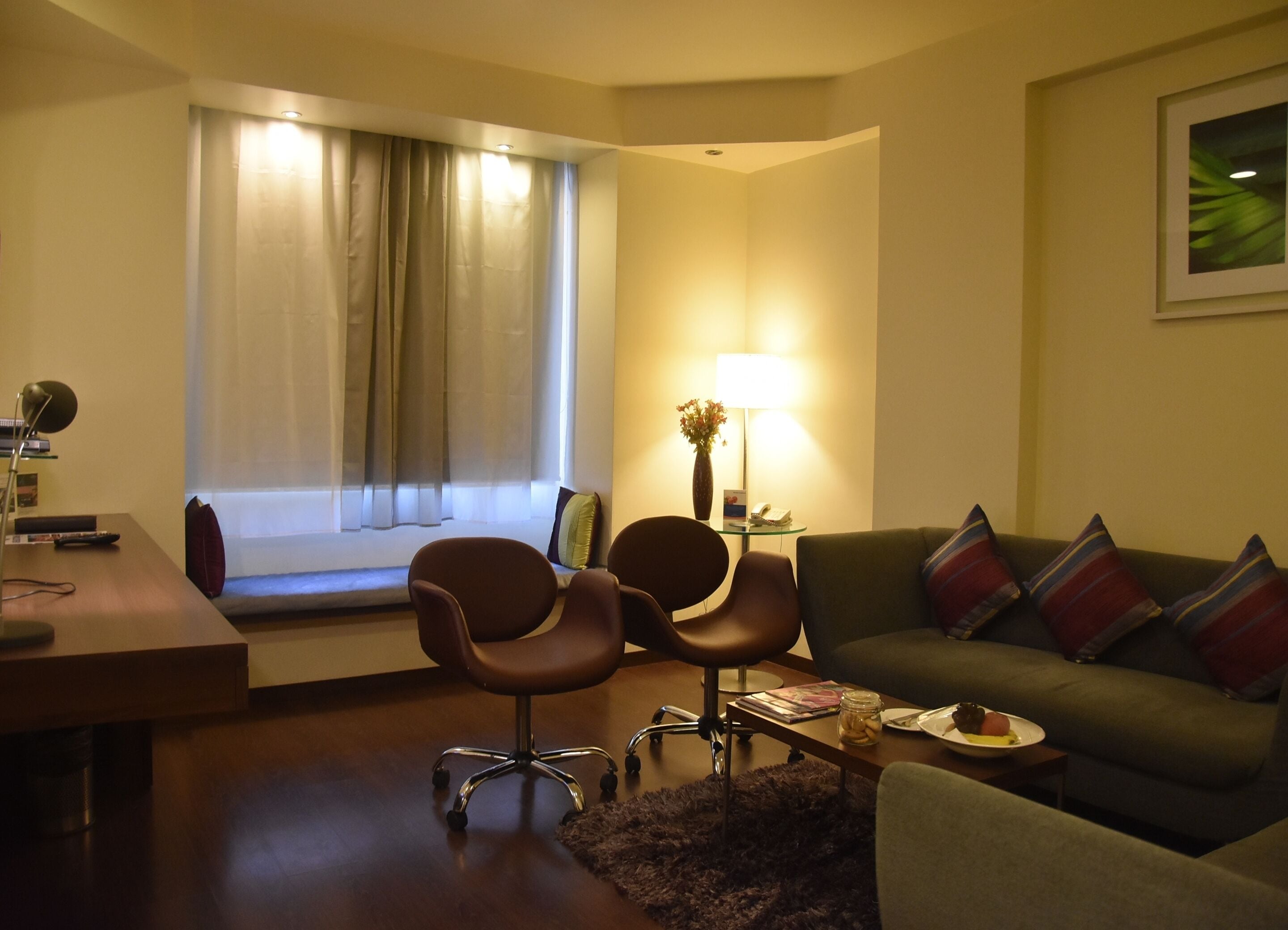 Un salon moderne comprenant un canapé, deux fauteuils, une table basse et une lampe.