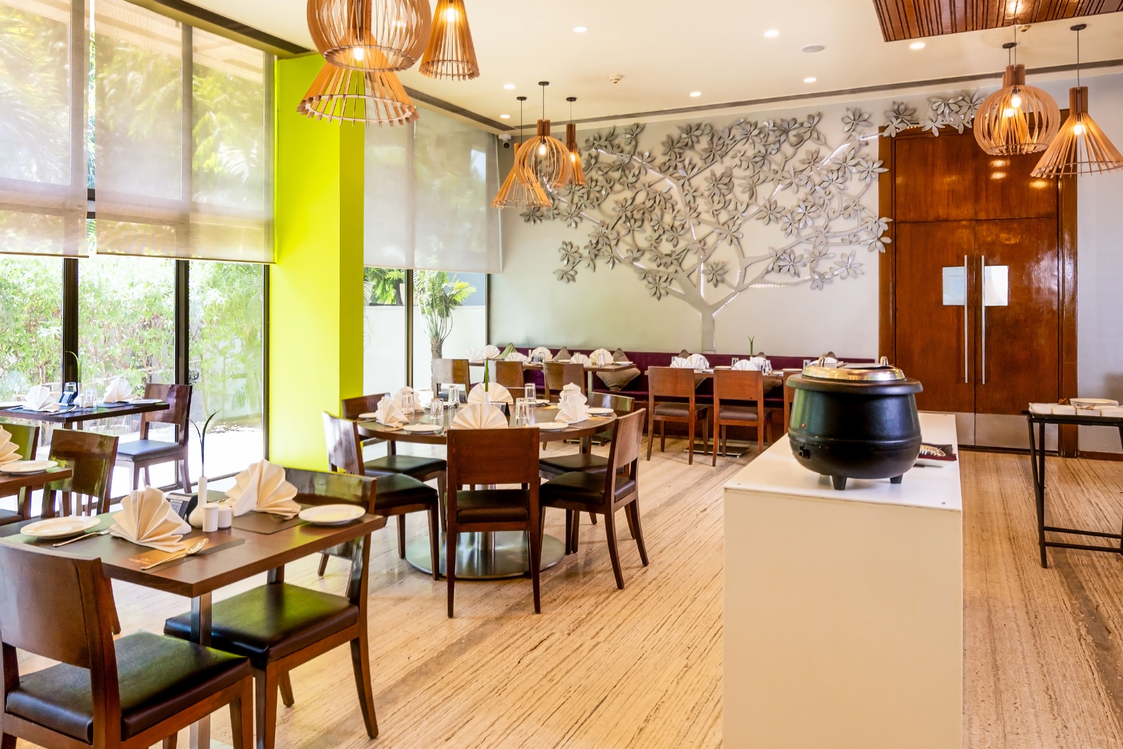 Un restaurant avec des tables rondes, des chaises en bois et des lampes suspendues.