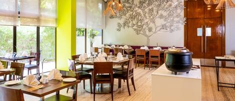 Un restaurant avec des tables rondes, des chaises en bois et des lampes suspendues.