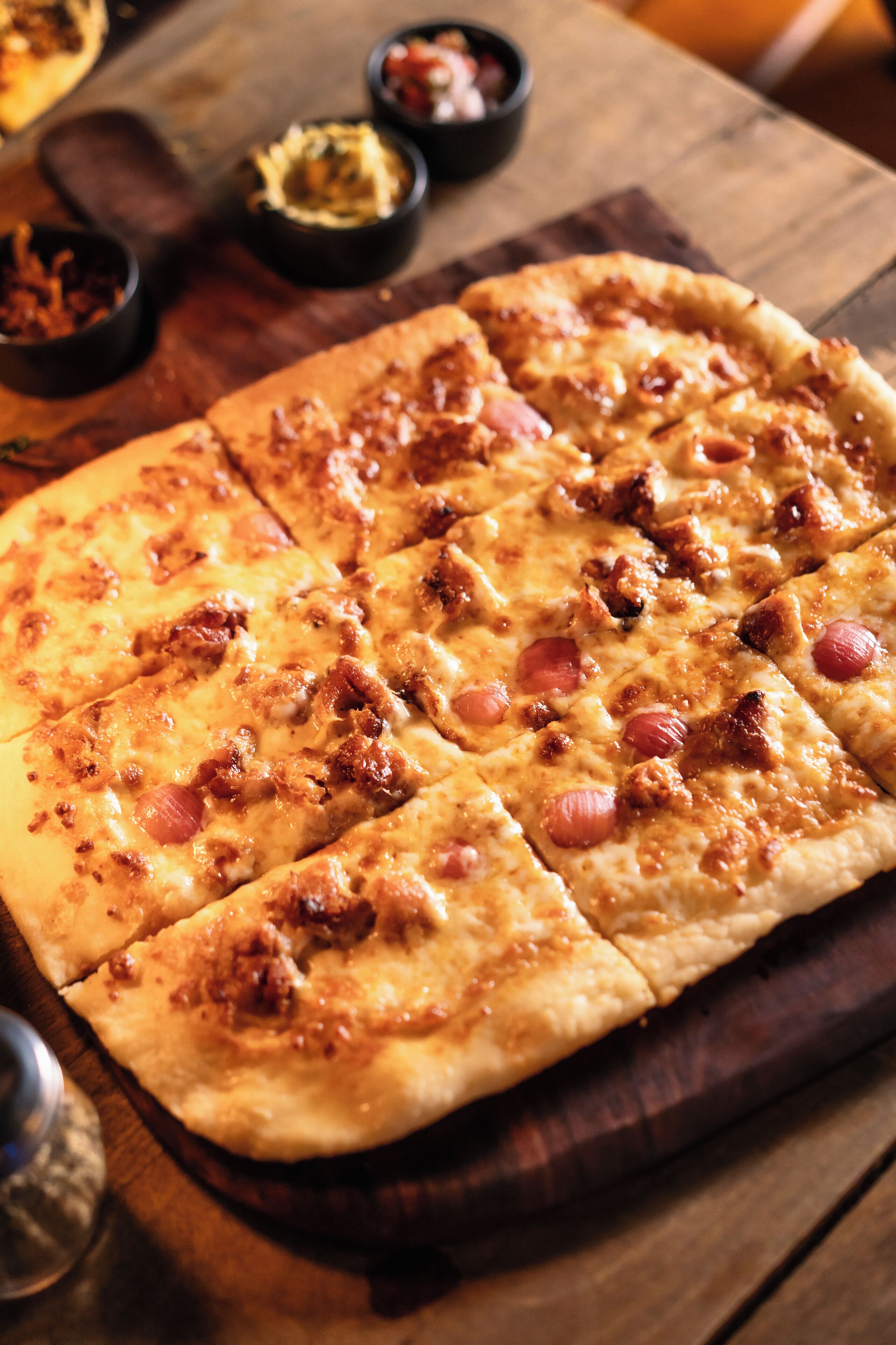 A pizza with various toppings on a wooden board.