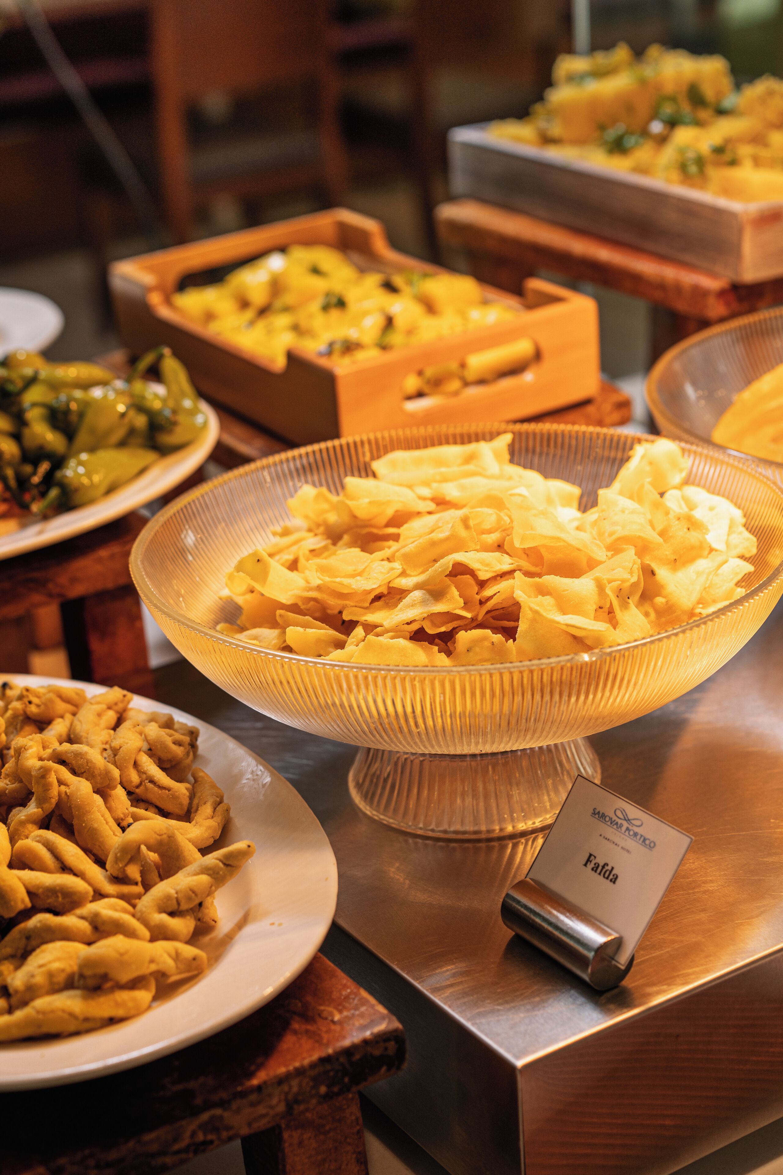 A buffet table with various dishes including chips, pasta, and a sign indicating 'Falda'.