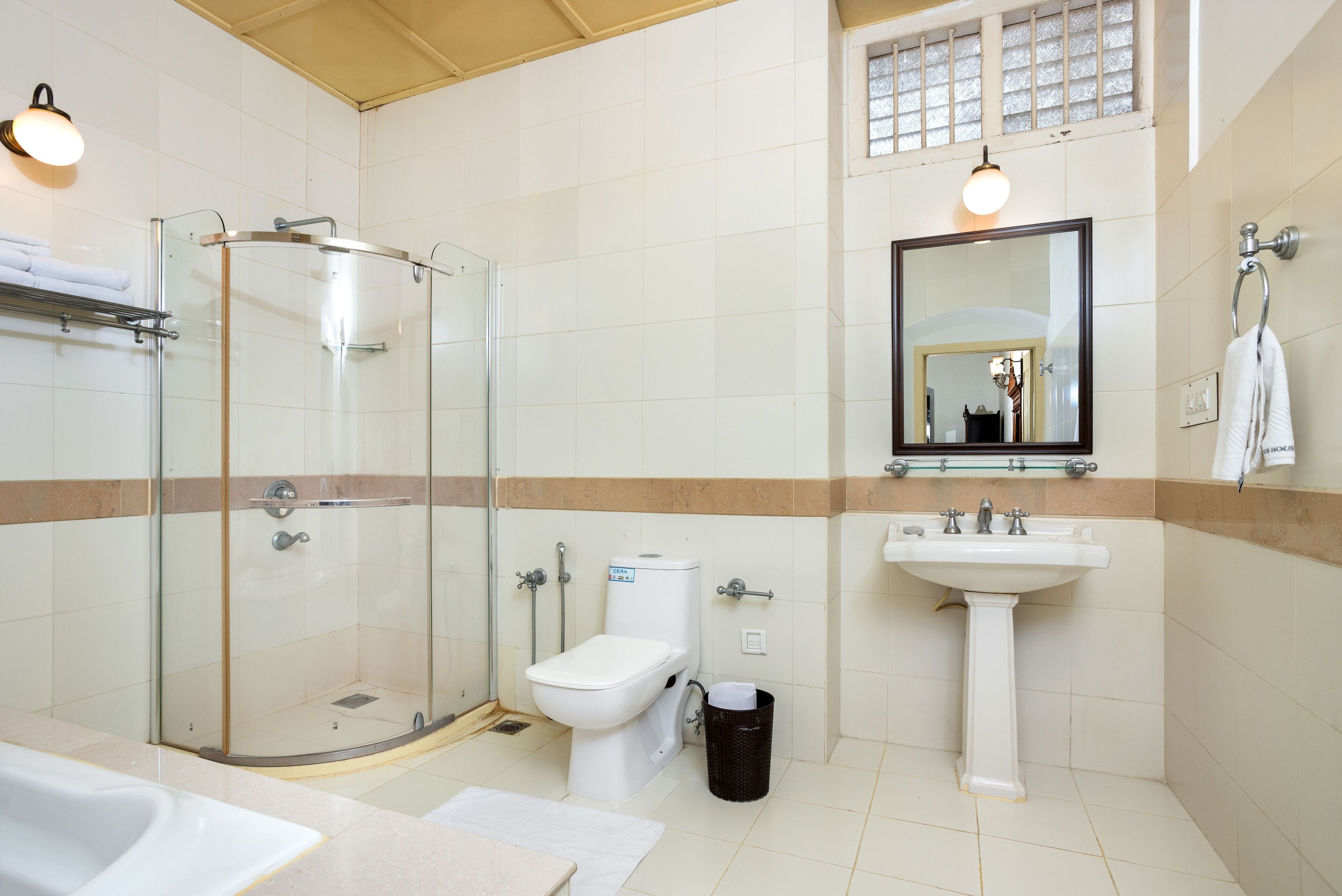 A bathroom with a glass-enclosed shower, a toilet, a sink, and a mirror.